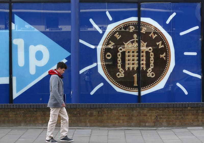 © Reuters. FILE PHOTO: A pedestrian passes an advertisement featuring a one penny piece in Wandsworth west London