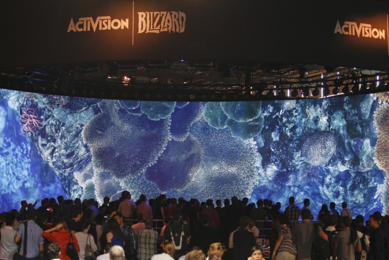 © Reuters. Visitors look at a presentation at the ActiVision Blizzard exhibition stand during the Gamescom 2013 fair in Cologne