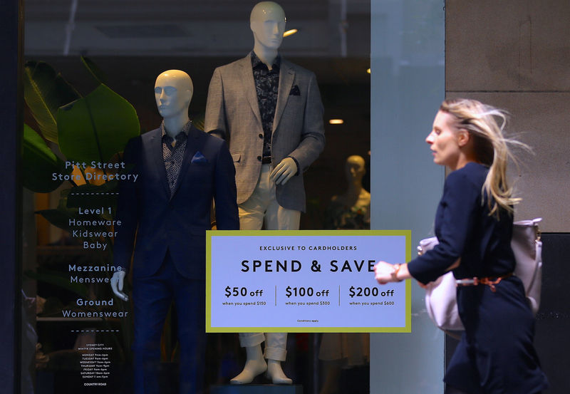 © Reuters. A shopper runs past a window of a retail store displaying products and a sale sign in central Sydney