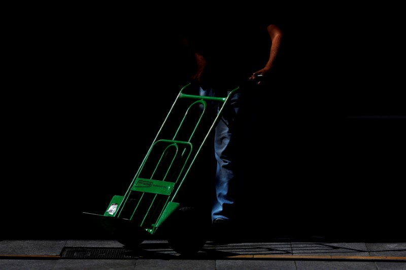 © Reuters. A worker pushes a cart on a street in downtown Ronda