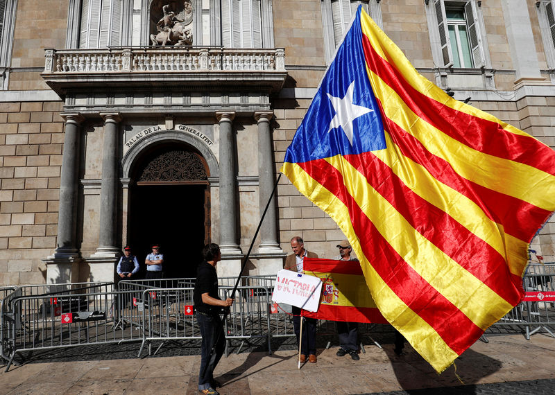 © Reuters. A man holding a Catalan separatist flag looks at men holding a Spanish flag outside the Generalitat Palace, the Catalan regional government headquarters in Barcelona