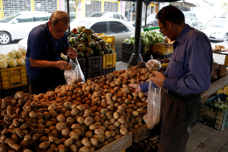 © Reuters. People select potatoes at a street market in Caracas