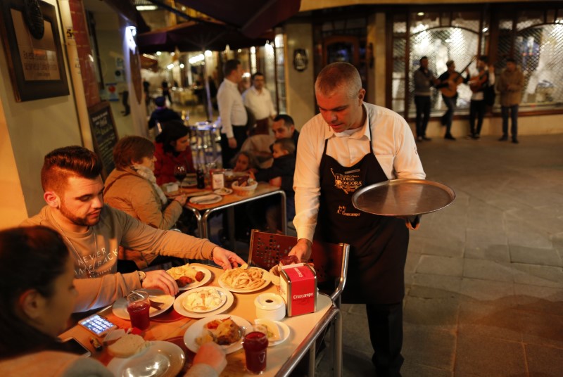 © Reuters. A waiter serves food to clients of a restaurant in the Andalusian capital of Seville, southern Spain