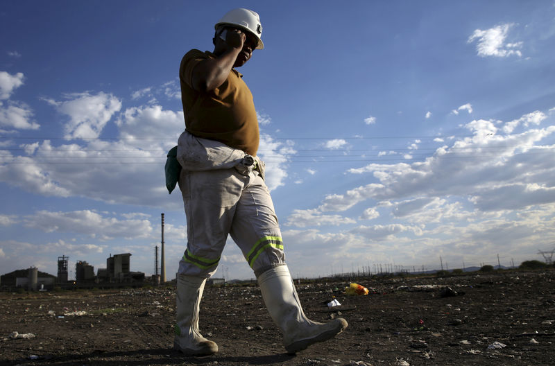 © Reuters. FILE PHOTO: A mine worker speaks on his mobile phone as he returns from the Lonmin mine at the end of his shift, outside Rustenburg