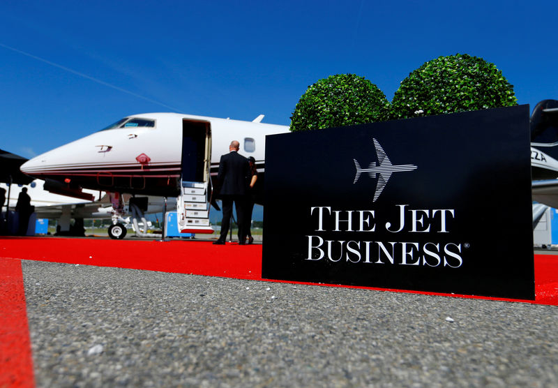 © Reuters. FILE PHOTO: Visitors stand next to an aircraft at the The Jet Business booth during EBACE in Geneva