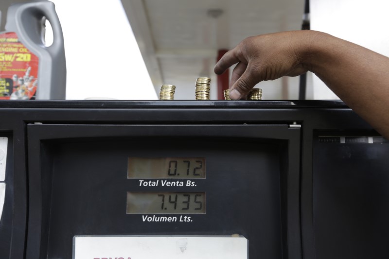 © Reuters. A gas station attendant piles up coins on top of a fuel dispenser at a gas station of state oil company Petroleos de Venezuela (PDVSA) before the government raised the price for fuel, in Caracas