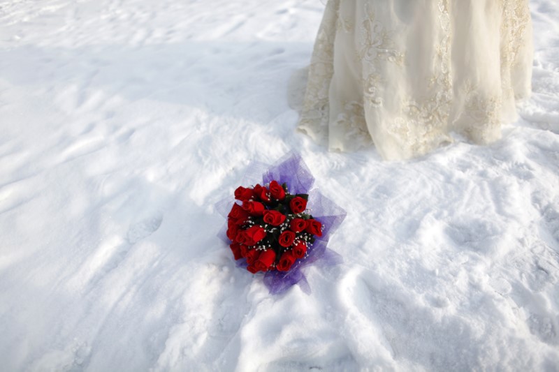 © Reuters. A bouquet is seen in the snow as a bride poses for a photograph after a group wedding ceremony during the 26th Harbin International Ice and Snow Festival in Harbin