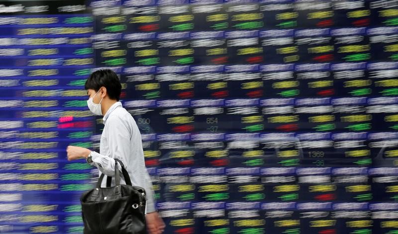 © Reuters. A man walks past an electronic stock quotation board outside a brokerage in Tokyo