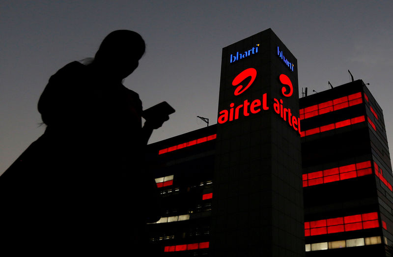 © Reuters. FILE PHOTO: A girl checks her mobile phone as she walks past the Bharti Airtel office building in Gurugram