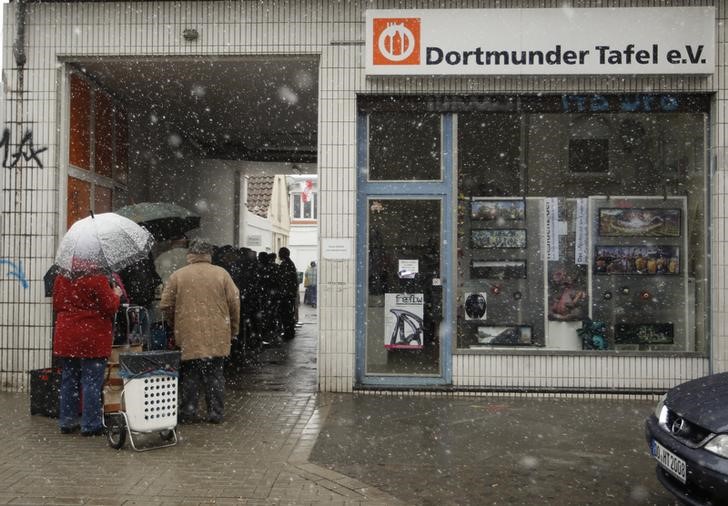 © Reuters. People line up during snow fall to receive food that is either to old or not looking nice enough for sale at the non-profit Dortmund food bank "Dortmunder Tafel"  in the western German city of Dortmund