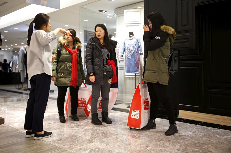 © Reuters. FILE PHOTO: Chinese tourists ask a sales assistant for directions at a Lotte department store in Seoul