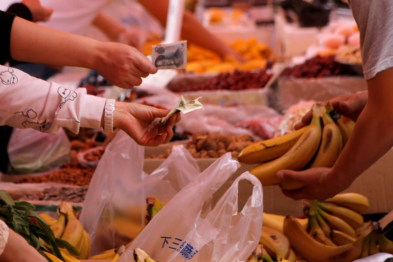 © Reuters. FILE PHOTO: Customers pay money as they purchase bananas at a market in Beijing