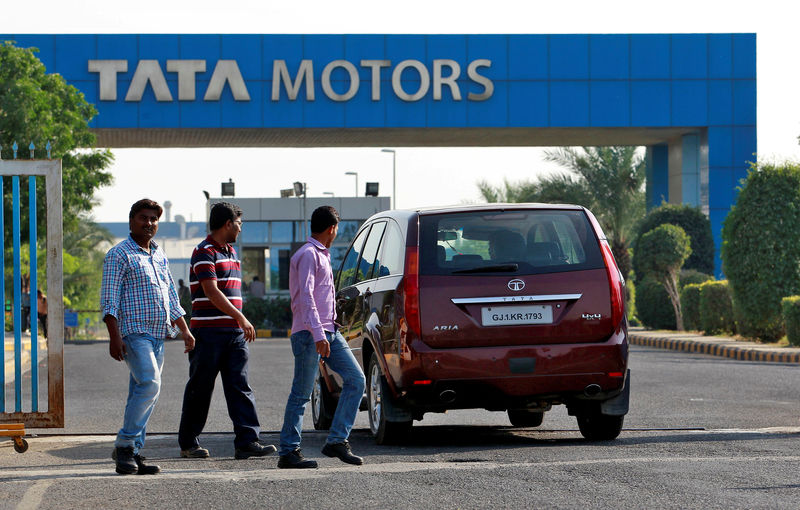 © Reuters. FILE PHOTO: A vehicle drives past three men walking out of a Tata Motors car plant at Sanand