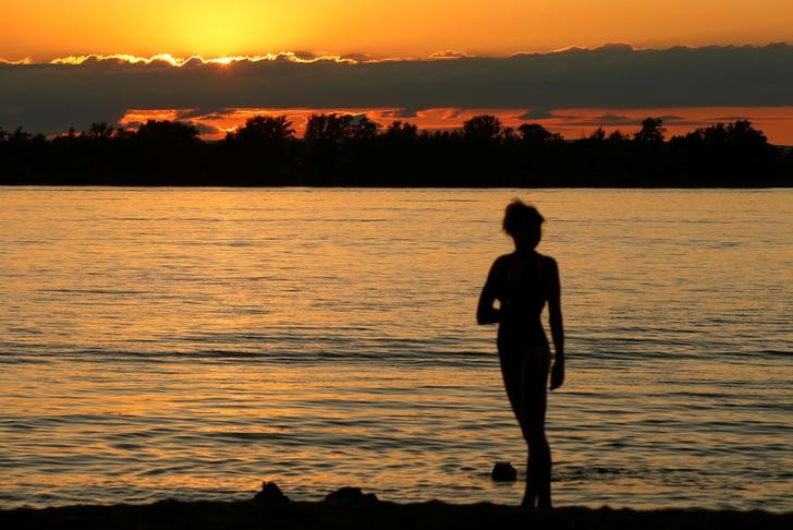 © Reuters. FILE PHOTO - Woman poses for a picture during sunset on the beach along the Volga river in Samara