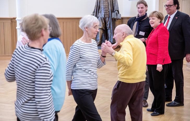 © Reuters. German Chancellor Angela Merkel watches pensioners dancing during her visit at the "Paul Gerhardt Stift" charity in Berlin