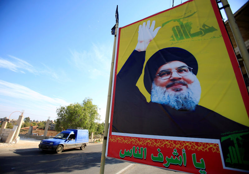 © Reuters. A car drives past a poster depicting Lebanon's Hezbollah leader Sayyed Hassan Nasrallah in Houla village