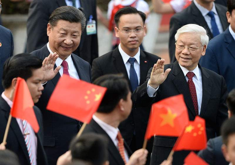 © Reuters. El presidente de China, Xi Jinping, y el secretario general del Partido Comunista de Vietnam, general Nguyen Phu Trong, saludan a estudiantes que agitan banderas vietnamitas y chinas durante una ceremonia de bienvenida en el palacio presidencial en Hanói