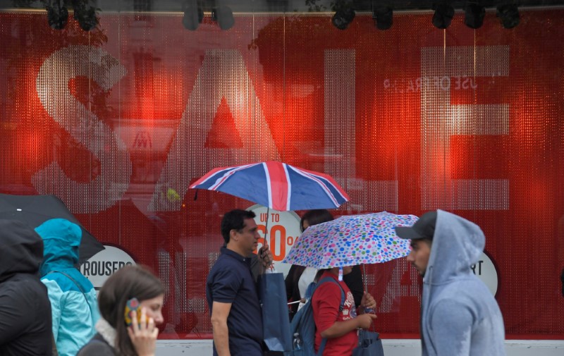 © Reuters. FILE PHOTO: Shoppers walk past a sale sign in central London