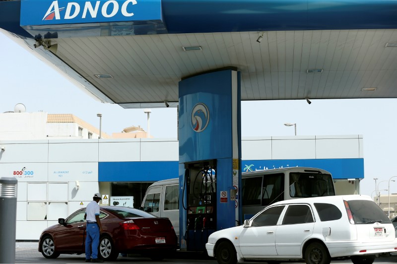 © Reuters. Worker injects a car with fuel at an ADNOC petrol station in Abu Dhabi