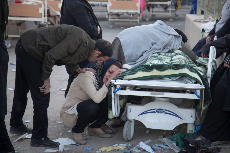 © Reuters. Mulher reage ao lado de corpo após terremoto atingir a província de Kermanshah, no Irã