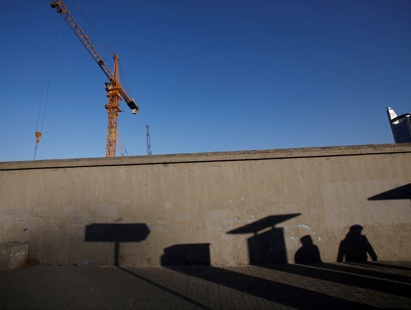 © Reuters. FILE PHOTO: Pedestrians cast their shadows  on a wall at a construction site in Beijing