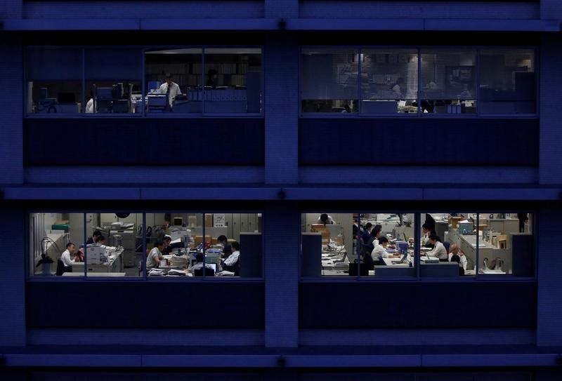 © Reuters. FILE PHOTO: Office workers are pictured through building windows during dusk in Tokyo