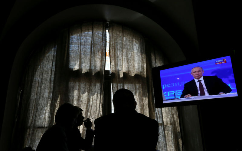 © Reuters. FILE PHOTO: People look at a screen at a media centre during Russian President Vladimir Putin's live broadcast nationwide phone-in in Moscow