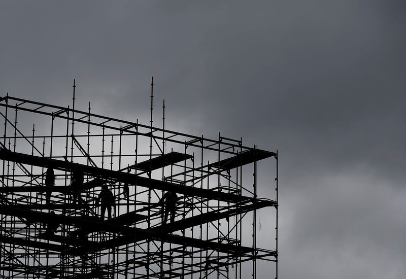 © Reuters. Workers are silhouetted on amongst scaffold at Potsdamer Platz square in Berlin