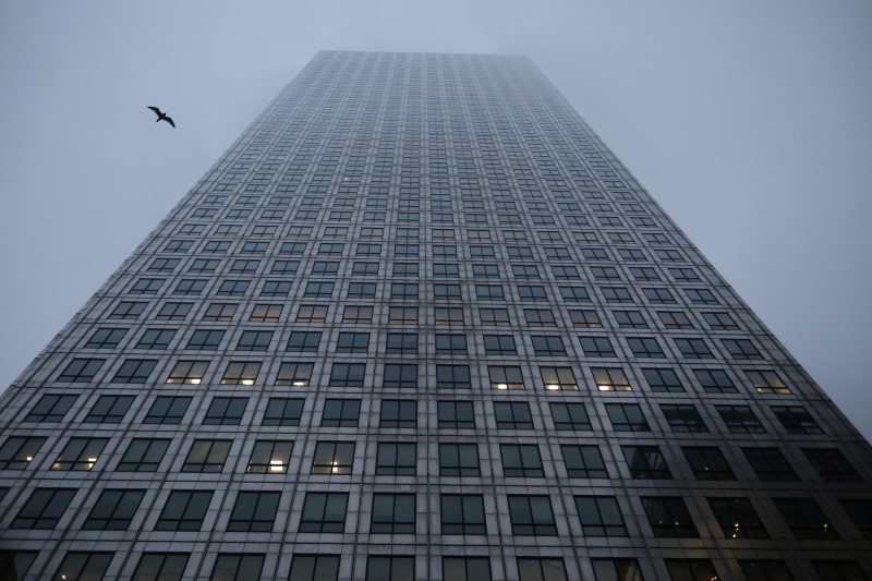 © Reuters. A bird flies between the buildings in the early morning mist in London's Canary Wharf financial district, Britain