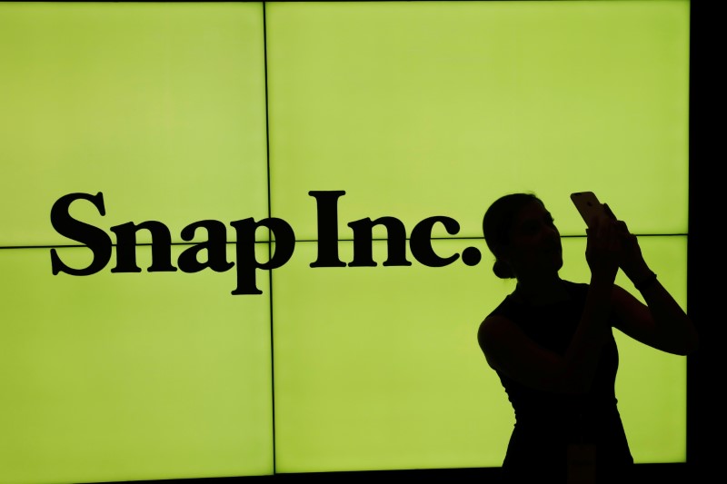 © Reuters. A woman stands in front of the logo of Snap Inc. on the floor of the New York Stock Exchange (NYSE) while waiting for Snap Inc. to post their IPO, in New York City