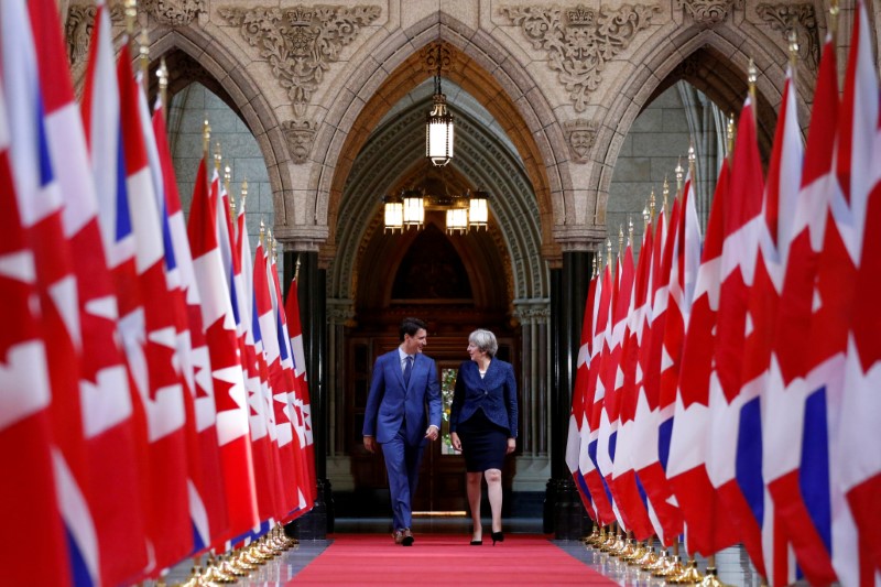© Reuters. Canada's PM Trudeau and Britain's PM May walk in the Hall of Honour on Parliament Hill in Ottawa