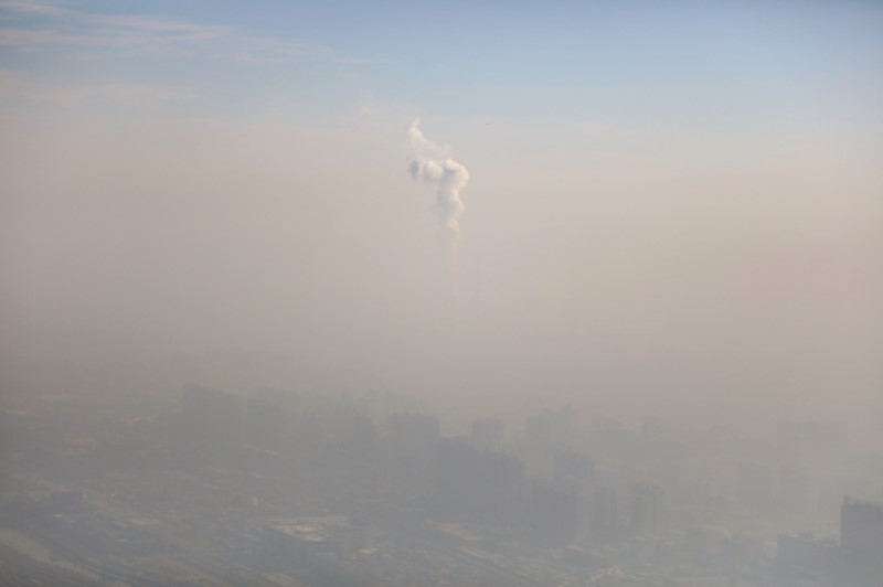 © Reuters. A chimney of a power plant is pictured among smog as a red alert for air pollution is issued in Beijing