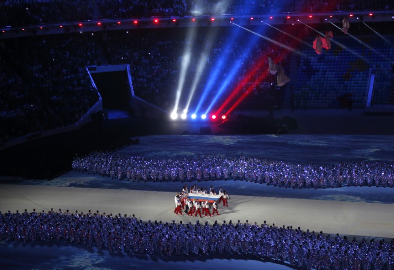 © Reuters. Russian athletes carry their national flag during the closing ceremony for the 2014 Sochi Winter Olympics