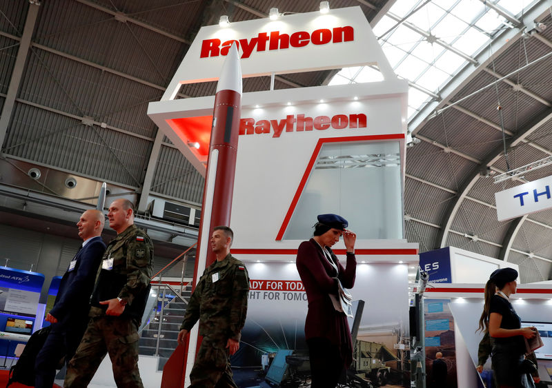 © Reuters. FILE PHOTO: People pass the U.S. defense company Raytheon stand at an international military fair in Kielce