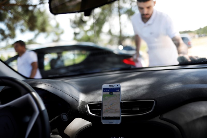 © Reuters. An Uber driver cleans his car as his cell phone shows the queue to pick up passengers departing Guarulhos International Airport in Sao Paulo