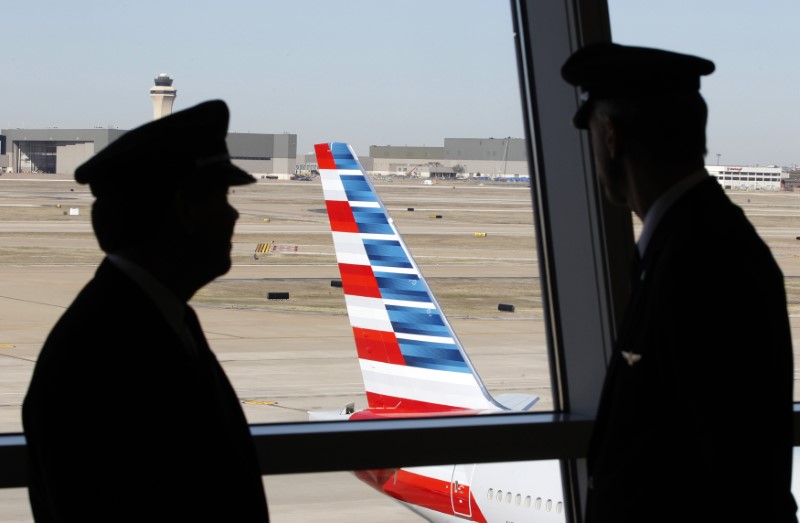 © Reuters. Pilots talk as they look at the tail of an American Airlines aircraft f at Dallas-Ft Worth International Airport
