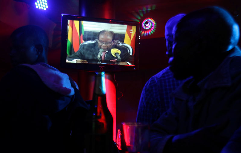 © Reuters. People watch as Zimbabwean President Robert Mugabe addresses the nation on television, at a bar in Harare