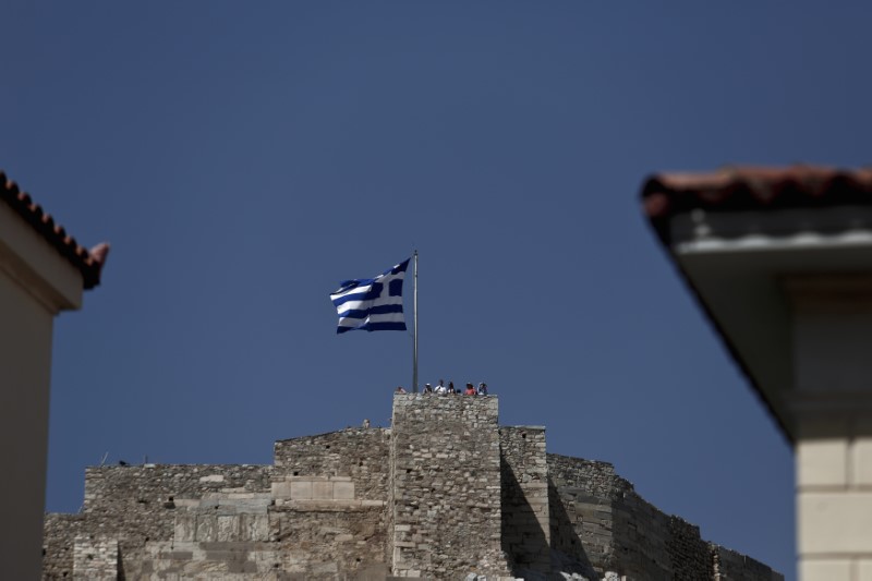 © Reuters. People stand near Greek flag at the Acropolis in Athens