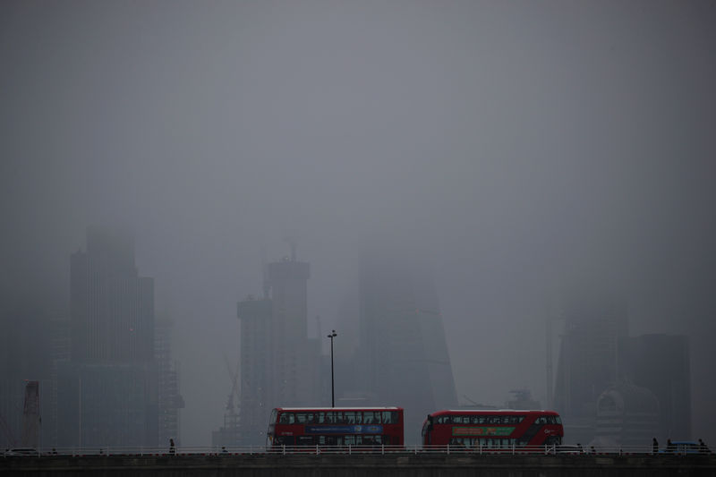 © Reuters. The City of London is partly obscured by morning fog, in London