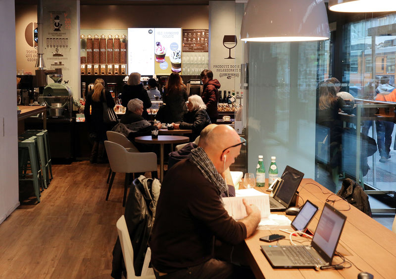 © Reuters. eople work inside the Intesa San Paolo bank in a open area next to cafe in Milan