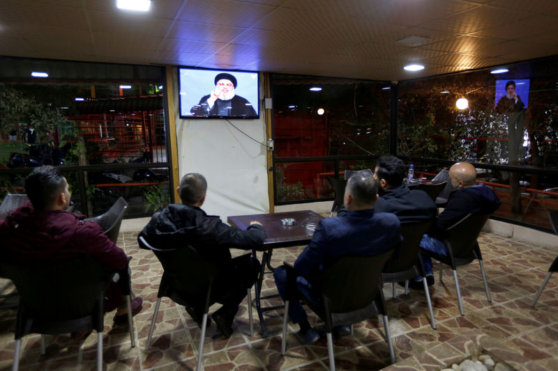 © Reuters. People watch Lebanon's Hezbollah leader Sayyed Hassan Nasrallah as he speas on television in Beirut