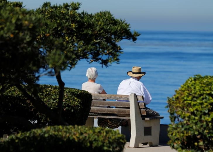 © Reuters. FILE PHOTO: An elderly couple looks out at the ocean as they sit on a park bench in La Jolla, California