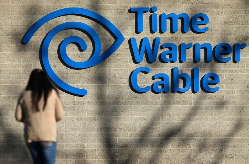 © Reuters. Un mujer camina frente al logo de Time Warner Cable en una oficina en San Diego