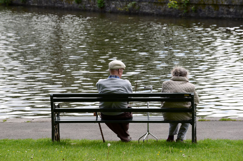 © Reuters. FILE PHOTO: Pensioners sit on a bench in a park in Merthyr Tydfil
