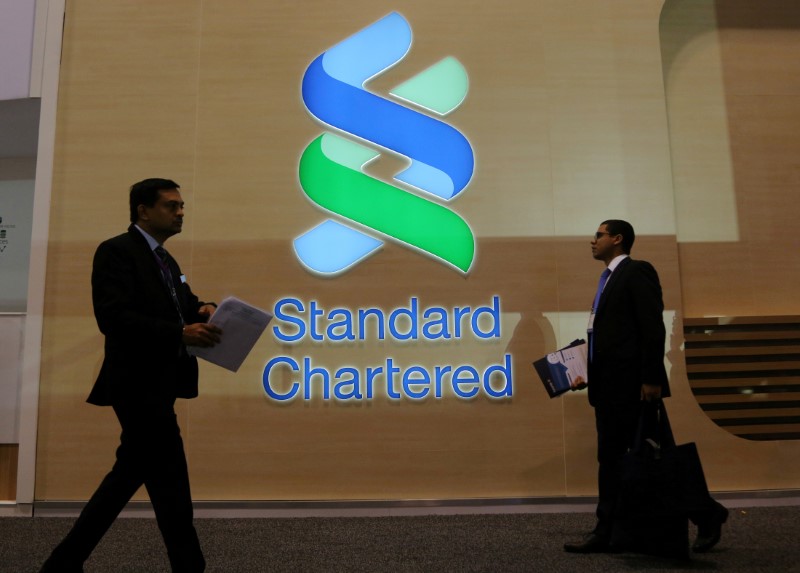 © Reuters. FILE PHOTO: People pass by the logo of Standard Chartered plc at the SIBOS banking and financial conference in Toronto