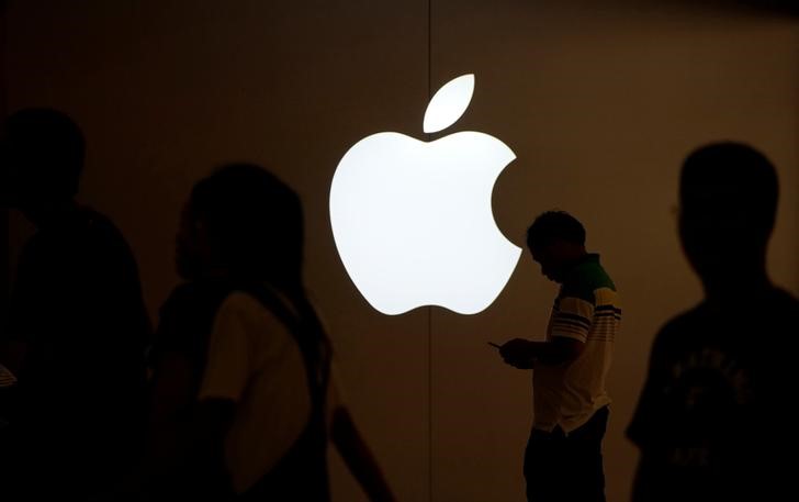 © Reuters. A man looks at the screen of his mobile phone in front of an Apple logo outside its store in Shanghai