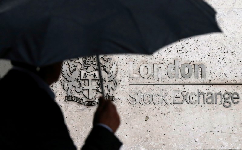 © Reuters. FILE PHOTO:A man shelters under an umbrella as he walks past the London Stock Exchange