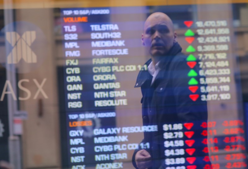 © Reuters. An investor is reflected in a window displaying a board showing stock prices at the Australian Securities Exchange in Sydney