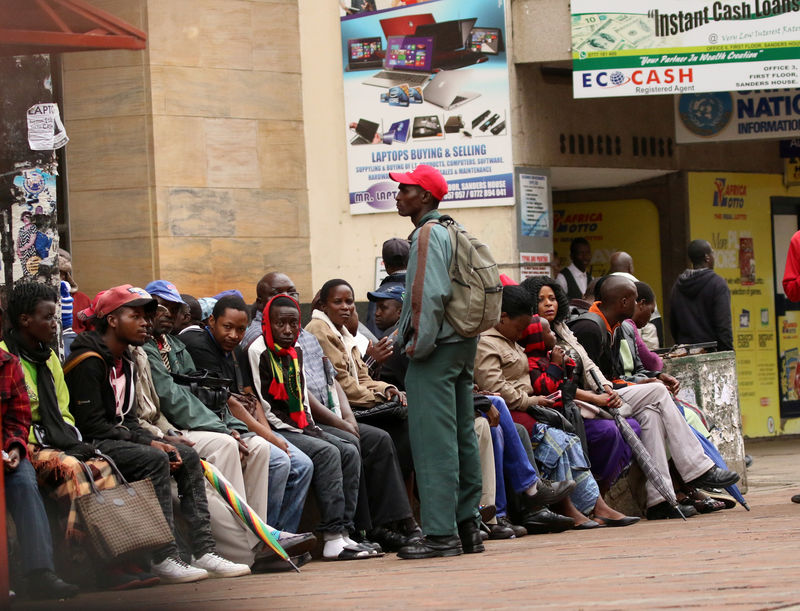 © Reuters. People queue to draw money outside a bank in Harare