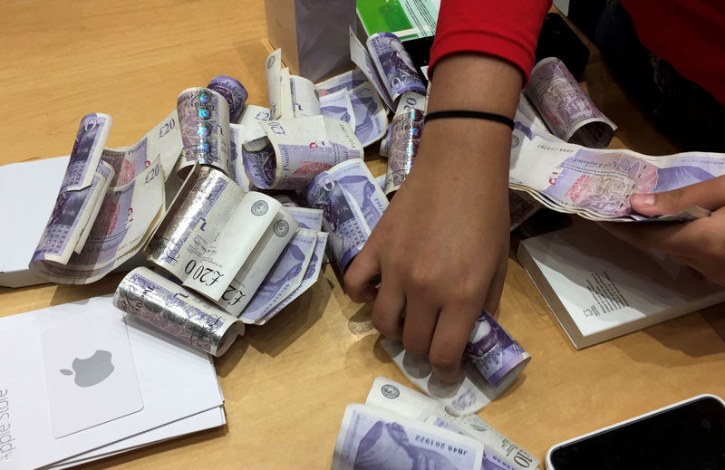 © Reuters. A shop assistant counts piles of British Pound Sterling banknotes at an Apple store in London